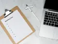 Planowanie harmonogramu zamawiania zaproszeń ślubnych, uwzględniając czas druku, to klucz do sukcesu. Na zdjęciu notatnik z listą zadań i laptop.