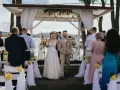 Para młoda idzie do ołtarza. Goście obserwują ceremonię, która może być ślubem cywilnym lub kościelnym.