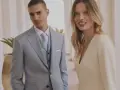 Elegancki jasny garnitur z błękitnym krawatem i kamizelką to idealna inspiracja, jak ubrać się na komunię jako gość. Kobieta w kremowej sukience prezentuje się równie stylowo.