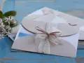 Eleganckie zaproszenia ślubne z różową wstążką. Gdy pojawią się przyczyny rezygnacji gości z udziału w weselu, warto wiedzieć, jak odmówić z klasą.