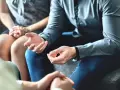 Rozmowa o tym, jakie są zasady etykiety przy odmawianiu na zaproszenie. Dłonie gestykulują, sugerując dyskusję.
