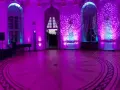Efektowne oświetlenie sali weselnej w odcieniach różu i błękitu, z rozproszonymi światłami, tworzy magiczną atmosferę idealną na zdjęcia i film.