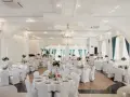 Elegancka sala weselna z białymi pokrowcami na krzesłach, sugerująca rezygnację z modeli tiffany na rzecz prostoty i klasy.
