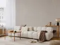 Minimalistyczny salon z sofą, stolikiem i lampą. Subtelne wzory na ścianie i dywanie podkreślają różnicę między stylem skandynawskim a japandi w oprawie eventu.