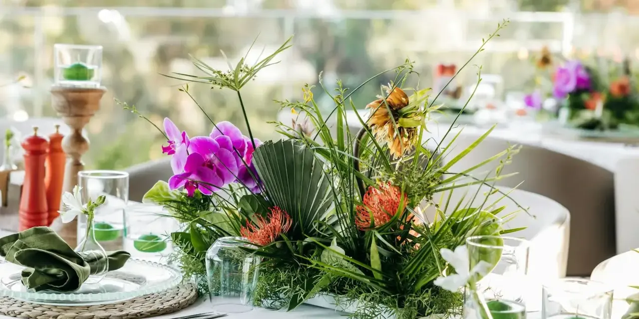 Stylowe podziękowania dla gości w duchu "less waste": bukiet z orchidei, protei i paproci, zielone serwetki, świece w szkle.