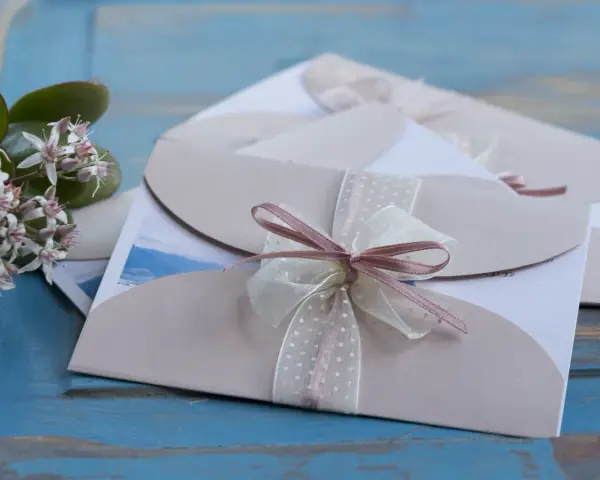Eleganckie zaproszenia ślubne z różową wstążką. Gdy pojawią się przyczyny rezygnacji gości z udziału w weselu, warto wiedzieć, jak odmówić z klasą.
