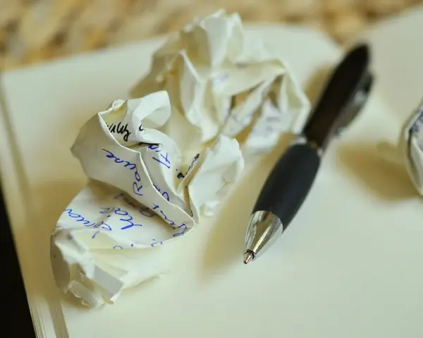 Zgniecione kartki z notatkami i długopis. Ilustruje, jakie są najczęstsze błędy w adresowaniu zaproszeń do par niebędących w małżeństwie.