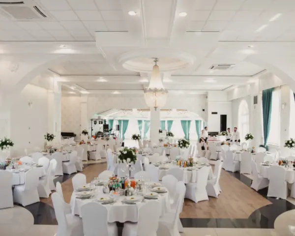 Elegancka sala weselna z białymi pokrowcami na krzesłach, sugerująca rezygnację z modeli tiffany na rzecz prostoty i klasy.