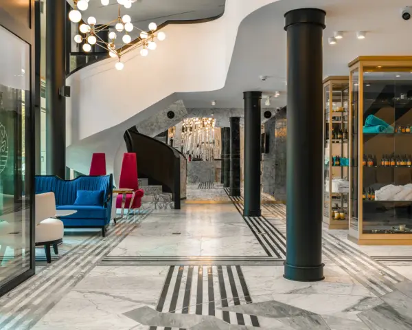 Eleganckie wnętrze bankietowe z niebieską kanapą i czerwonymi fotelami. Przyczyny powrotu do stylistyki art deco w nowoczesnych wnętrzach bankietowych widać w geometrycznych wzorach i luksusowych materiałach.