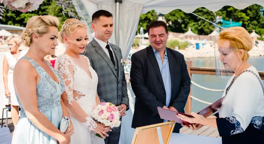 Ślub cywilny z panną młodą, panem młodym, świadkami i urzędniczką w przyłbicy.