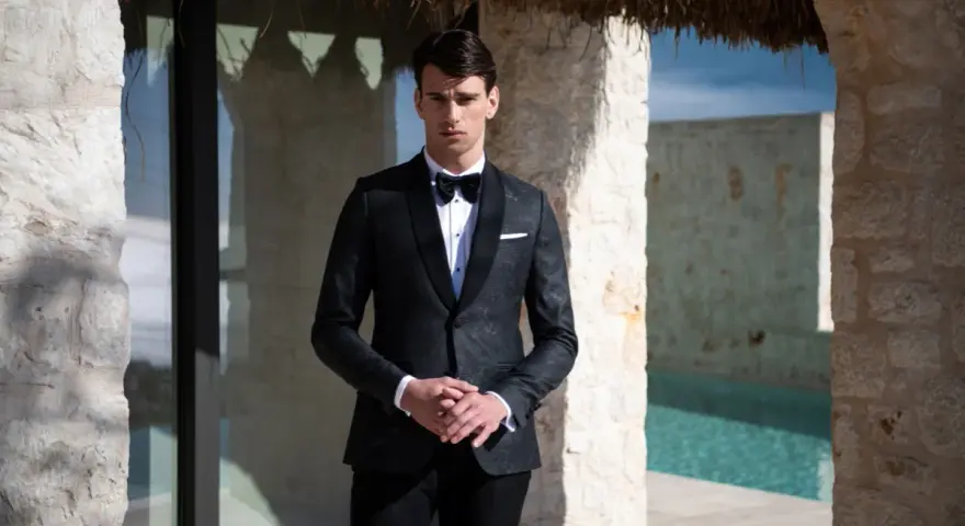 Elegancki mężczyzna w smokingu, idealny przykład stroju black tie na wesele. Różnica między ubiorem black tie a cocktail dress dla gości weselnych jest widoczna.