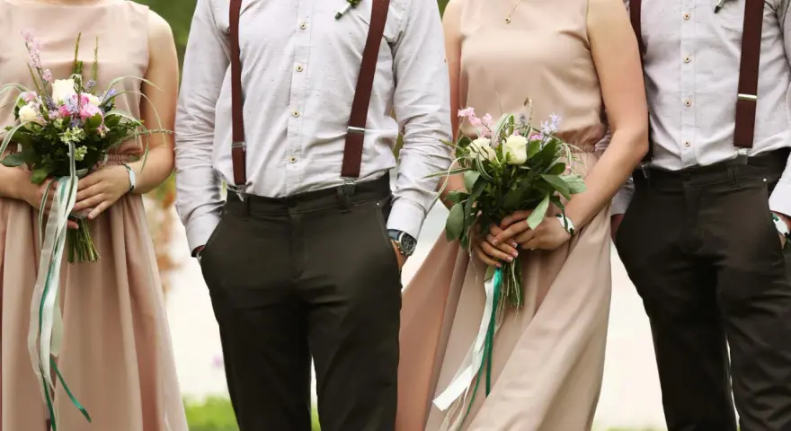 Eleganckie stroje pary z bukietami. Brak informacji o dress codzie na zaproszeniu mógłby prowadzić do takich stylizacji.