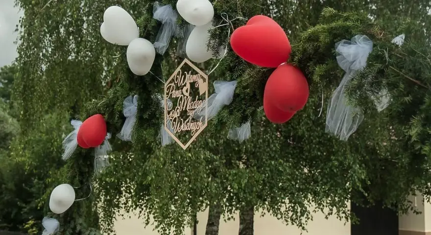 Brama weselna z balonami i napisem "Witamy Parę Młodą". Tradycja bram weselnych to symboliczne powitanie nowożeńców przez gości.