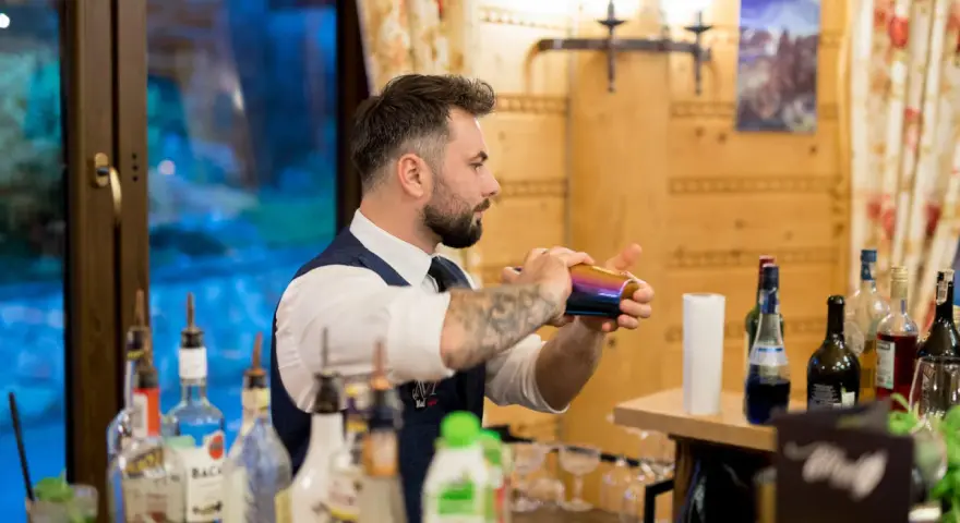 Barman przygotowuje drinki. Czy warto inwestować w barmana i drink bar na weselu? Koszty a efekt - zobacz!