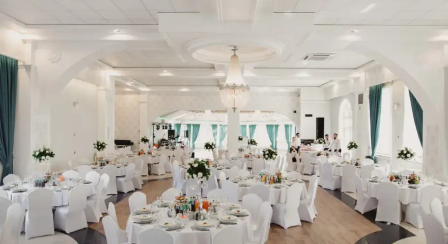 Elegancka sala weselna z białymi pokrowcami na krzesłach, sugerująca rezygnację z modeli tiffany na rzecz prostoty i klasy.