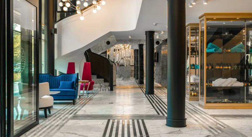 Eleganckie wnętrze bankietowe z niebieską kanapą i czerwonymi fotelami. Przyczyny powrotu do stylistyki art deco w nowoczesnych wnętrzach bankietowych widać w geometrycznych wzorach i luksusowych materiałach.