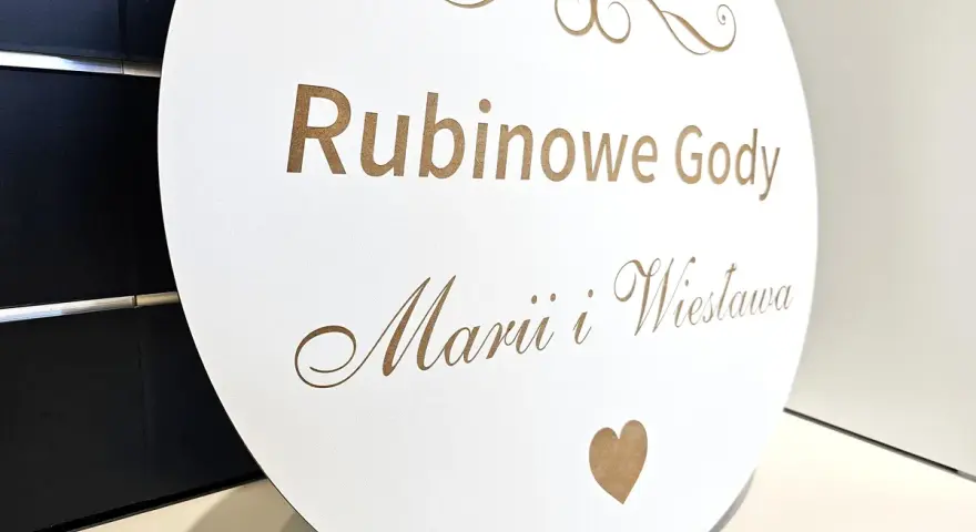 Okrągła tablica z napisem "Rubinowe Gody Marii i Wiesława" i cyfrą "40" upamiętnia 40 rocznicę ślubu.