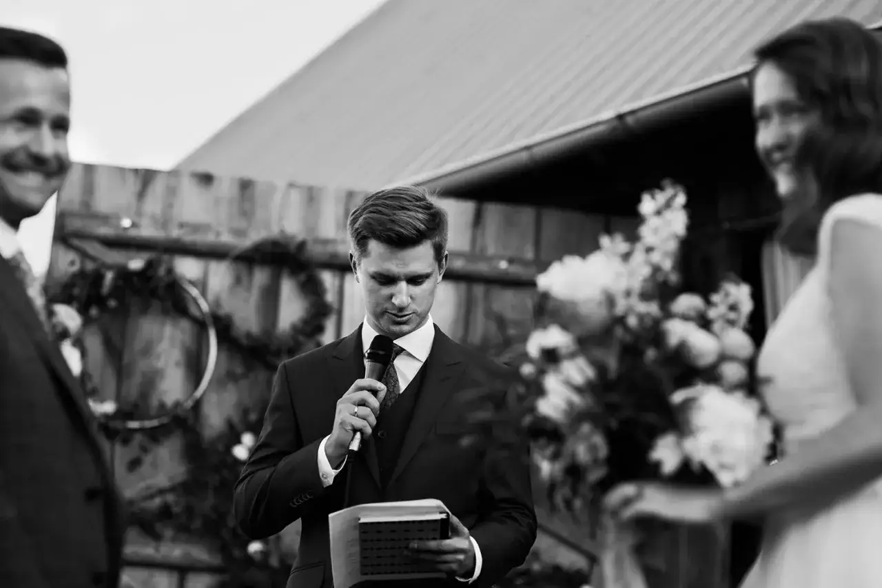 Mężczyzna z mikrofonem i księgą, podczas ceremonii ślubnej. Różnica między ślubem humanistycznym, cywilnym a konkordatowym.