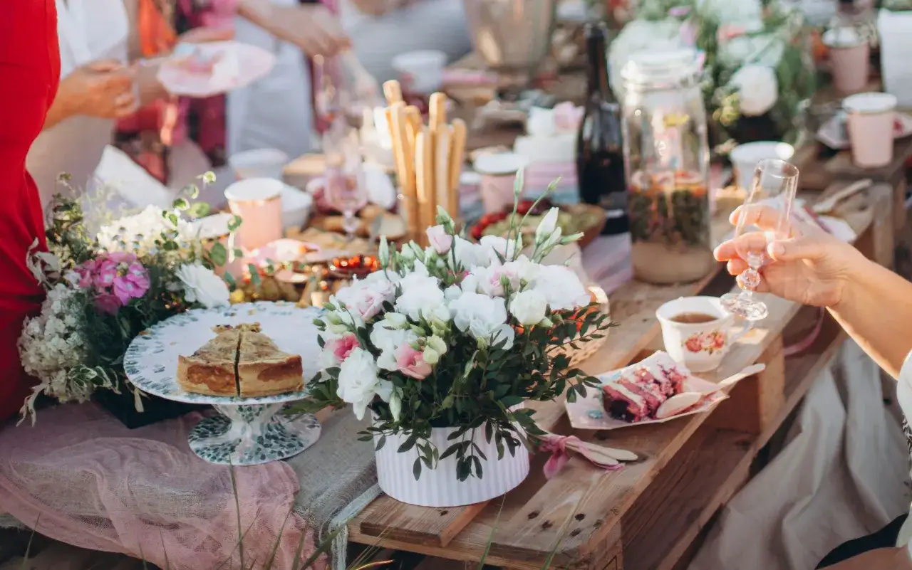 Kwiaty w stylu boho chic i rustykalnym na stole piknikowym. Delikatne róże i hortensje podkreślają różnicę między stylami.