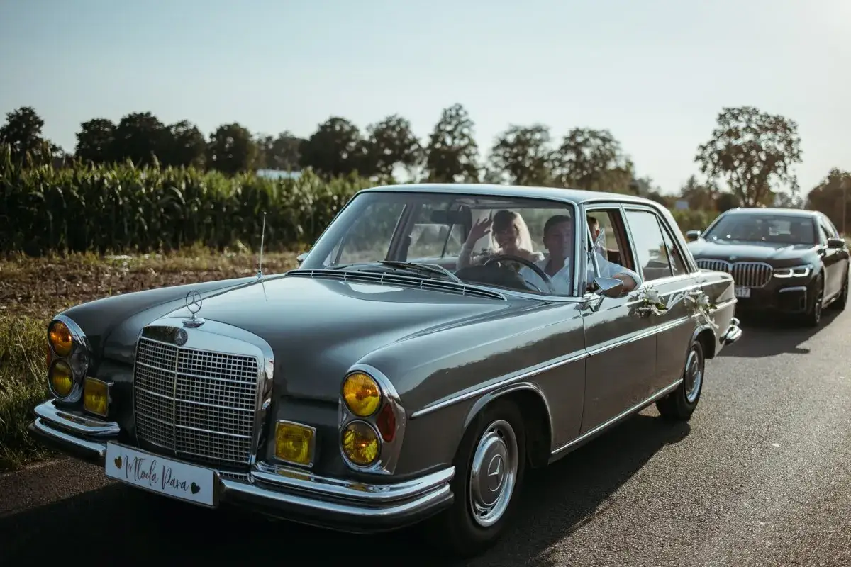 Para gości przyjezdnych, jak zaplanować noclegi i transport? Logistyka weselna w stylu retro, z parą młodą w klasycznym Mercedesie.
