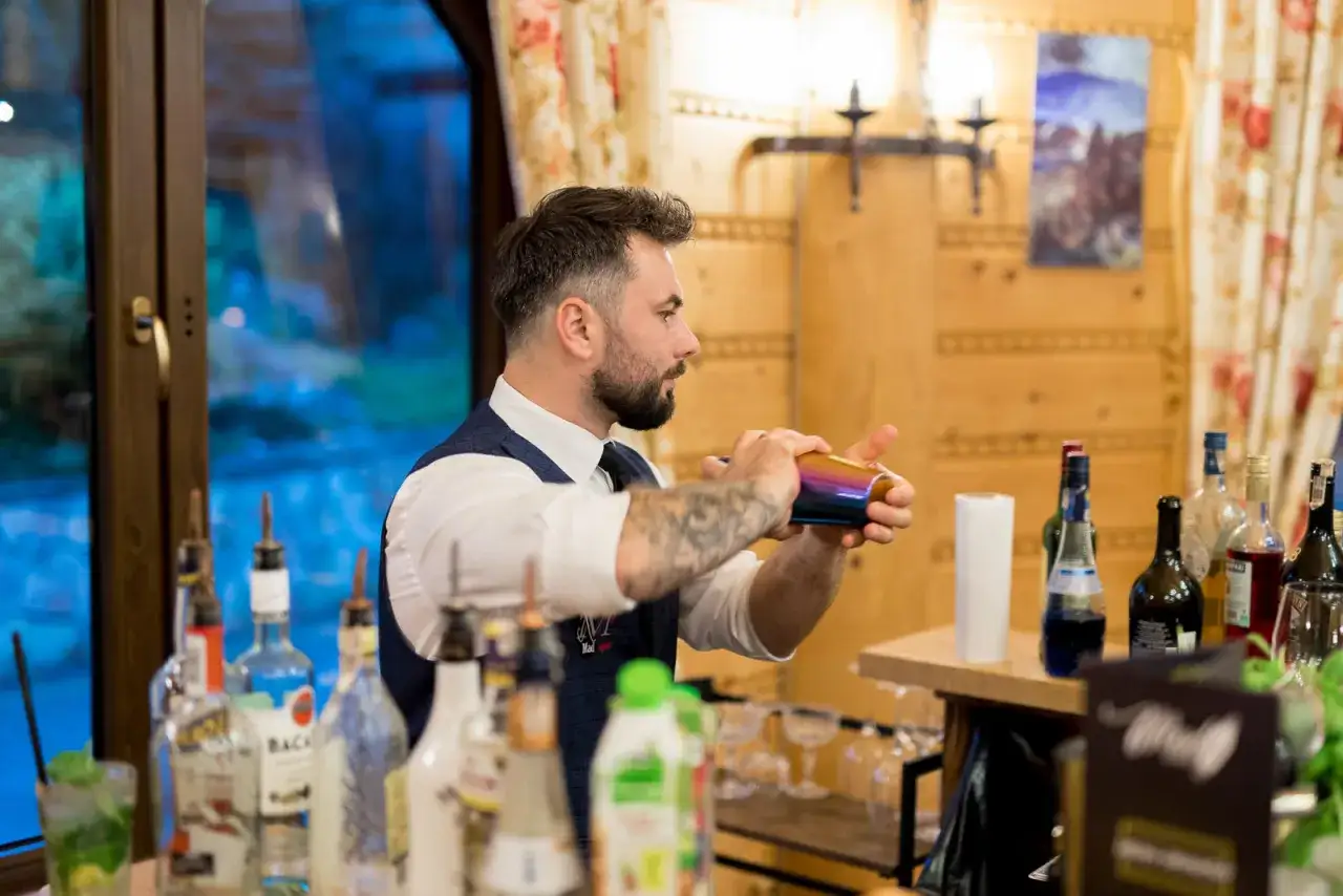 Barman przygotowuje drinki. Czy warto inwestować w barmana i drink bar na weselu? Koszty a efekt – zobacz!