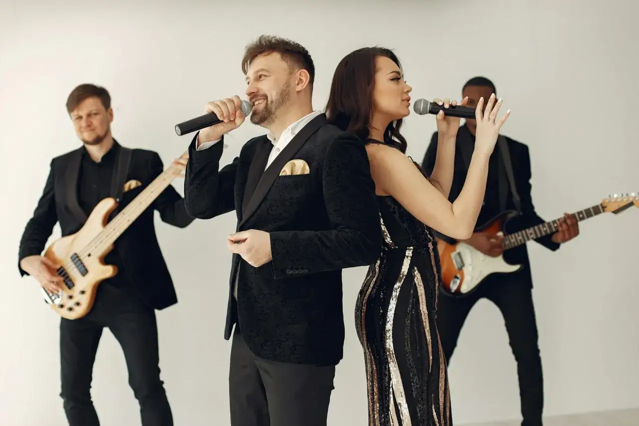 Zespół muzyczny z wokalistami i gitarzystami. Czy warto wynająć muzyków grających na żywo do obiadu? Taka oprawa muzyczna z pewnością uświetni każdą uroczystość.