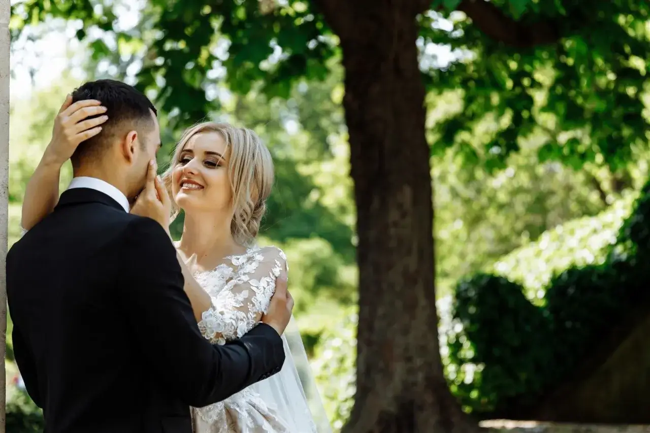 Panna młoda uśmiecha się do narzeczonego, czule go dotykając. Jak uniknąć objawów stresu przedślubnego i