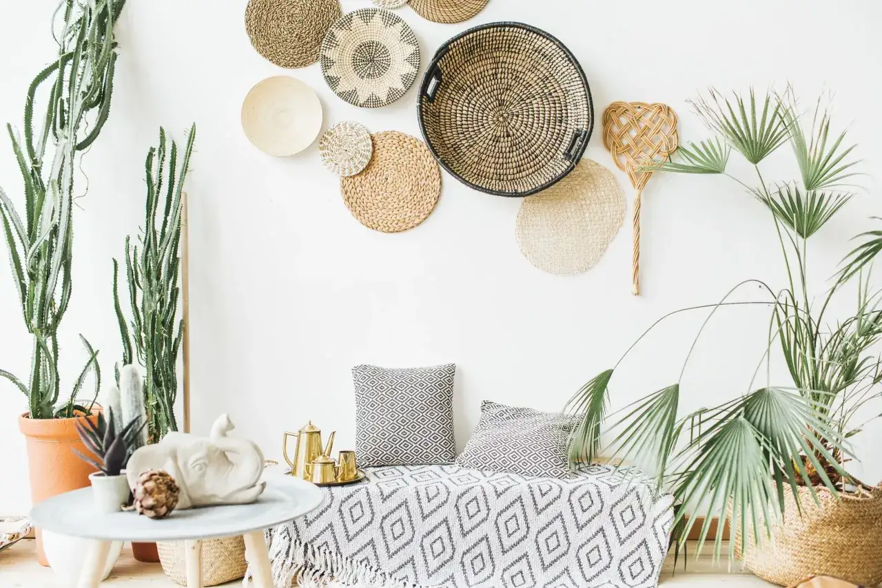 Boho styl: jak uniknąć przesytu dekoracjami? Wnętrze z plecionymi koszami, roślinami i geometrycznymi wzorami.