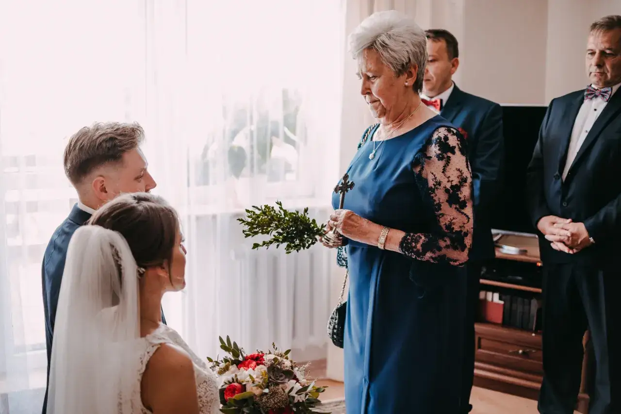Babcia błogosławi parę młodą krzyżem i gałązkami bukszpanu. Widać przyczyny powrotu do tradycji błogosławieństwa w domu rodzinnym.