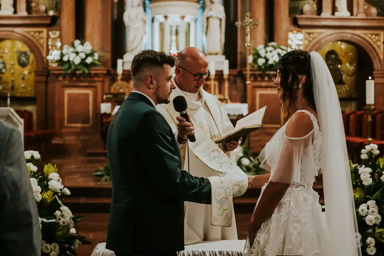 Ślub konkordatowy w 2026 roku: para młoda, ksiądz czytający z księgi, białe kwiaty. Jakie dokumenty do ślubu konkordatowego są potrzebne?